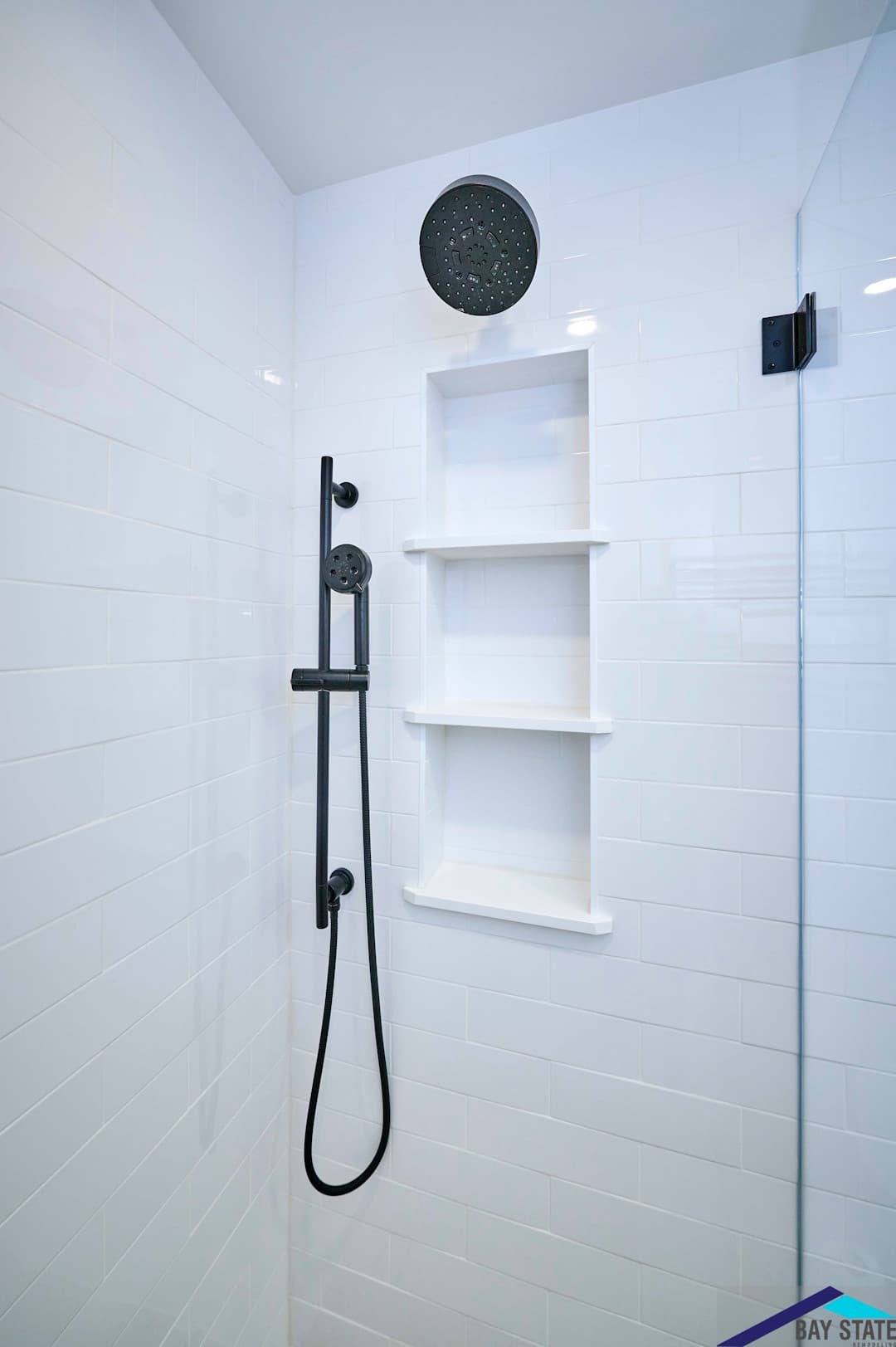 Harvey St. Cambridge renovated bathroom shower with black rain shower head, handheld sprayer, and tiled niche