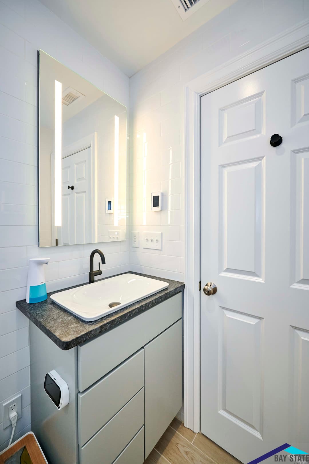 Renovated Harvey St. Cambridge bathroom, gray floating vanity with black stone counter and backlit mirror