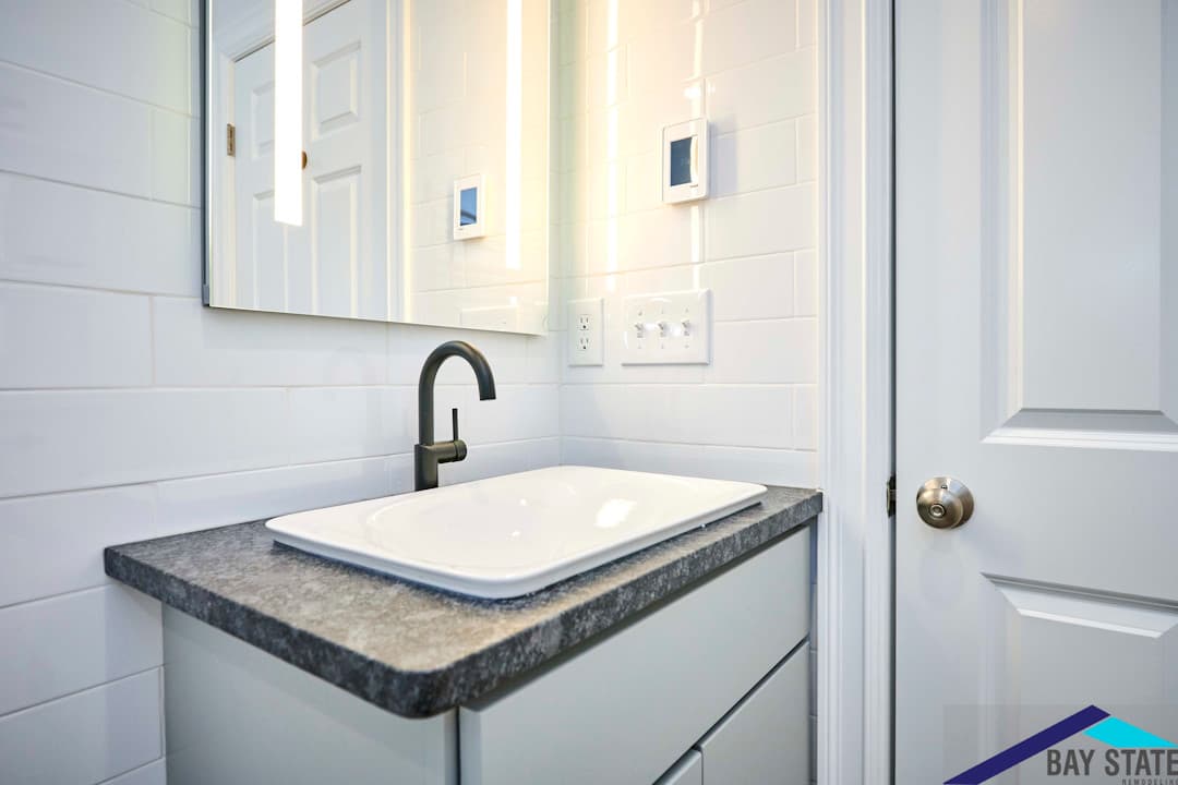 Harvey St. Cambridge renovated bathroom vanity detail, black faucet, white vessel sink, speckled stone countertop