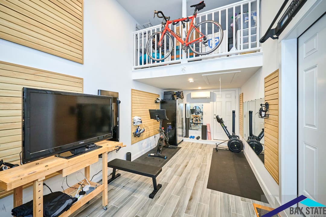 Harvey St. Cambridge home gym with a lofted storage mezzanine, wood slat walls, and tile flooring