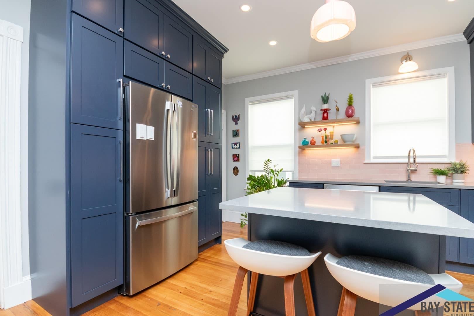Dalrymple St. Jamaica Plain kitchen after remodel, navy cabinetry framing a stainless fridge and floating shelves