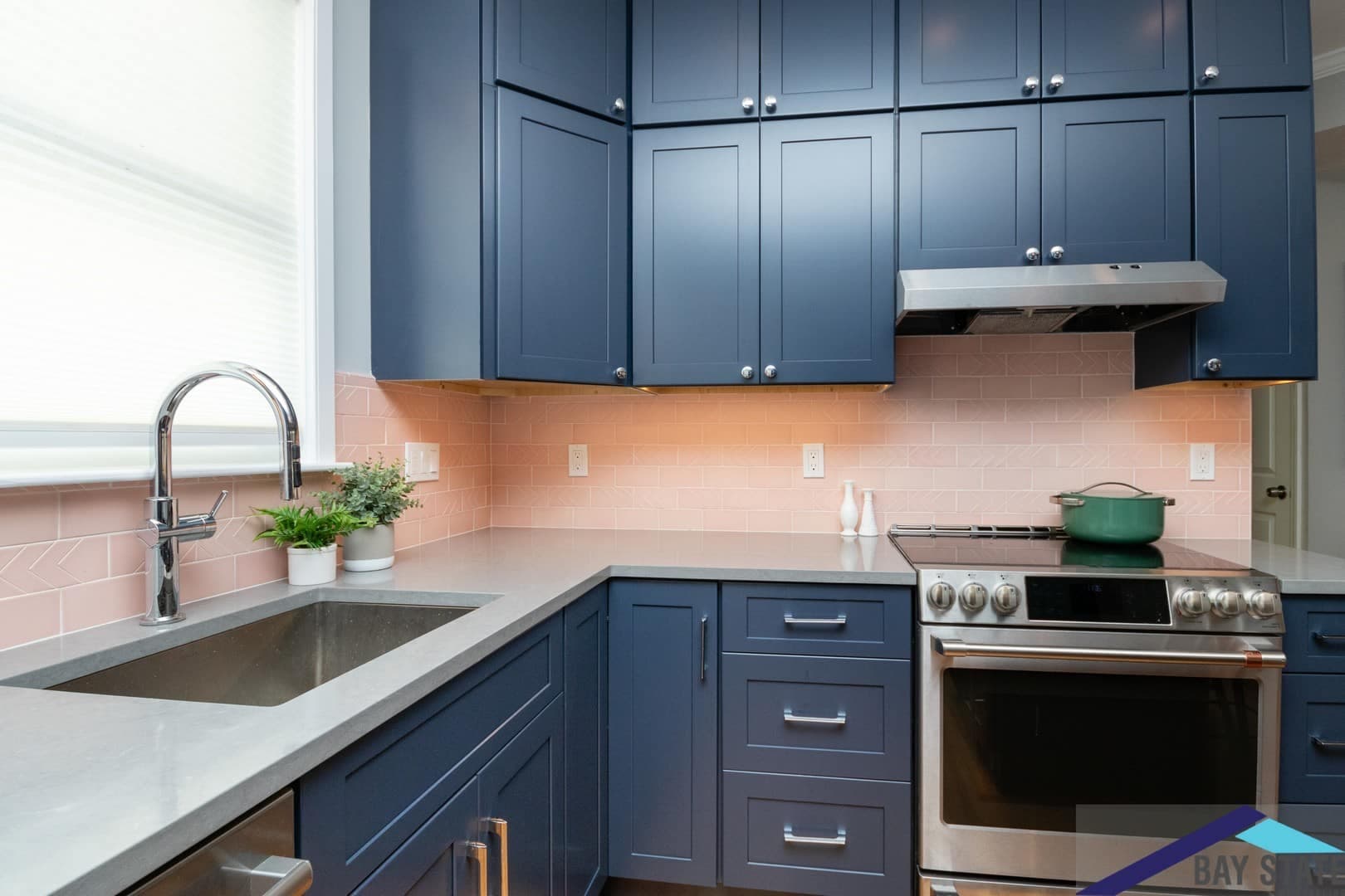 Dalrymple St. Jamaica Plain kitchen after remodel, navy cabinets and stainless range beneath a vented hood
