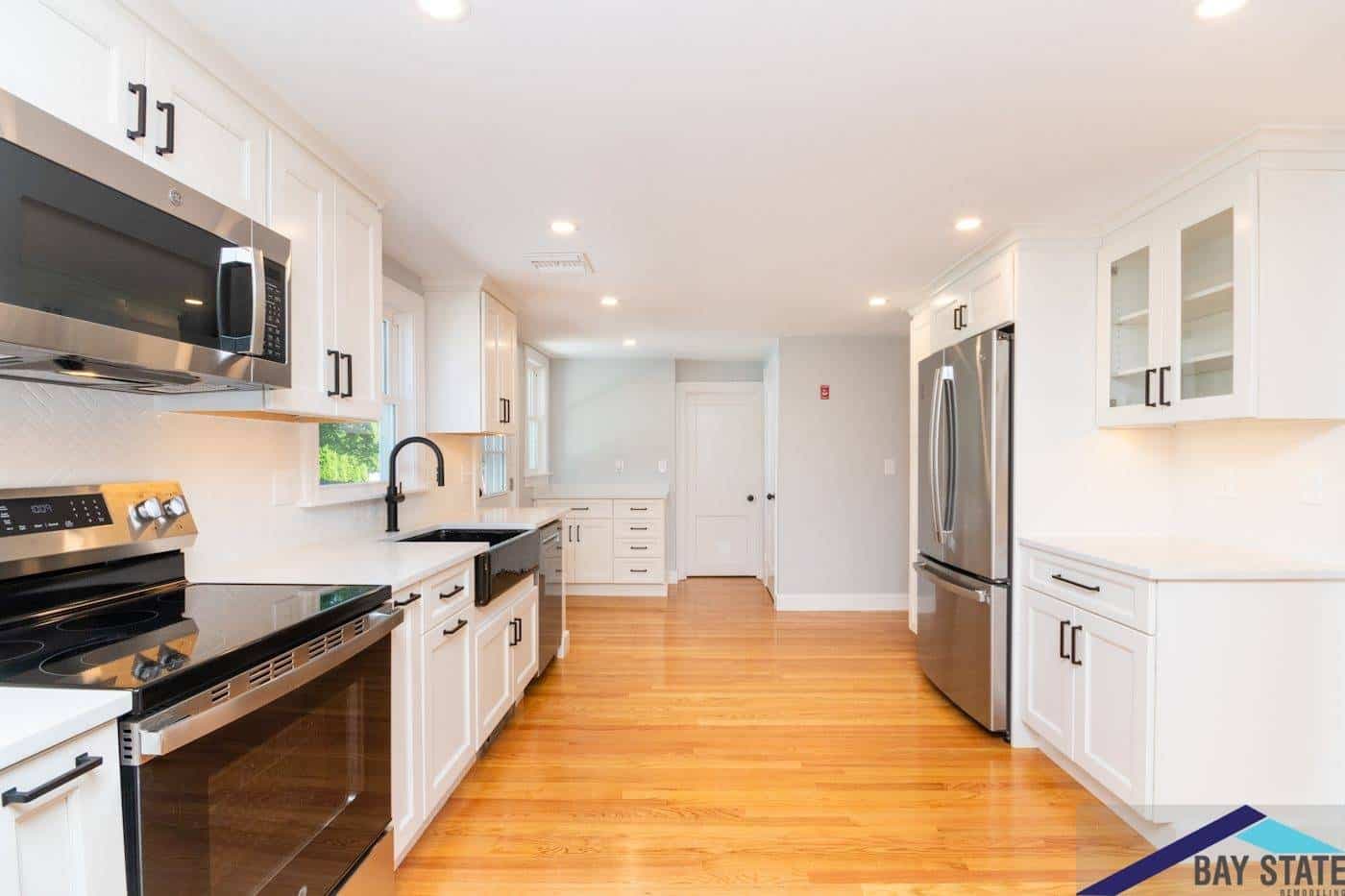 Bowker St. Waltham kitchen with white cabinets, black hardware, black quartz counters, and farmhouse sink