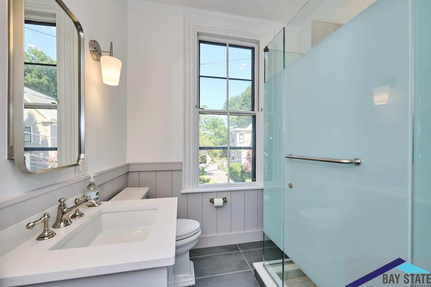 Renovated Tennyson St. Somerville bathroom with white vanity, chrome fixtures, and a frosted blue glass shower