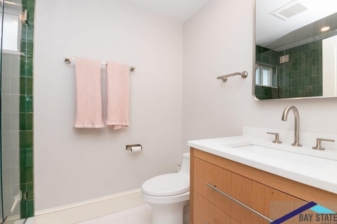 Renovated Trowbridge Ave. Newton bathroom with wood vanity, quartz counter, chrome fixtures, and pink hand towels