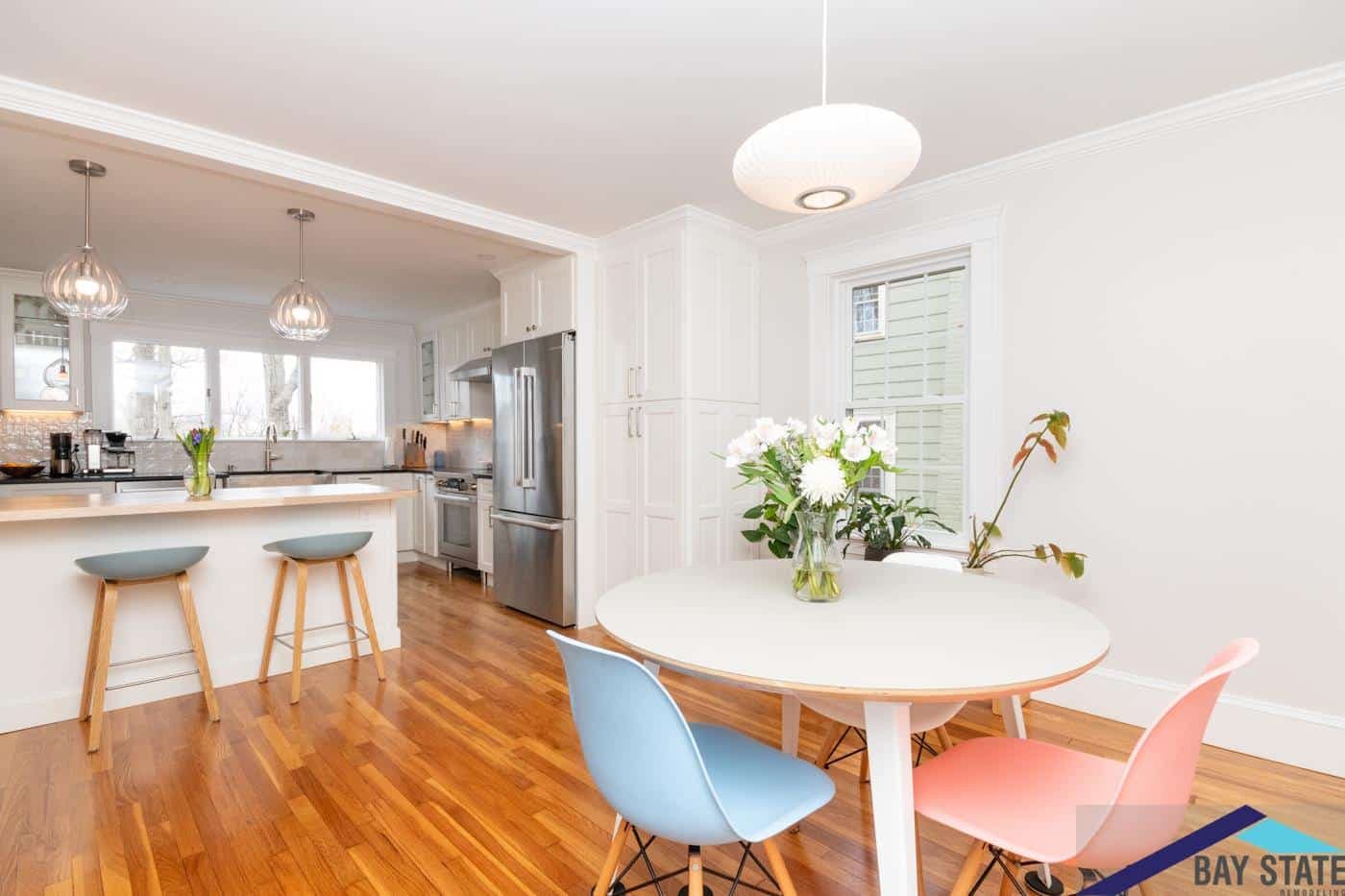 Renovated Trowbridge Ave. Newton kitchen with white cabinets, stainless fridge, and pendant lighting