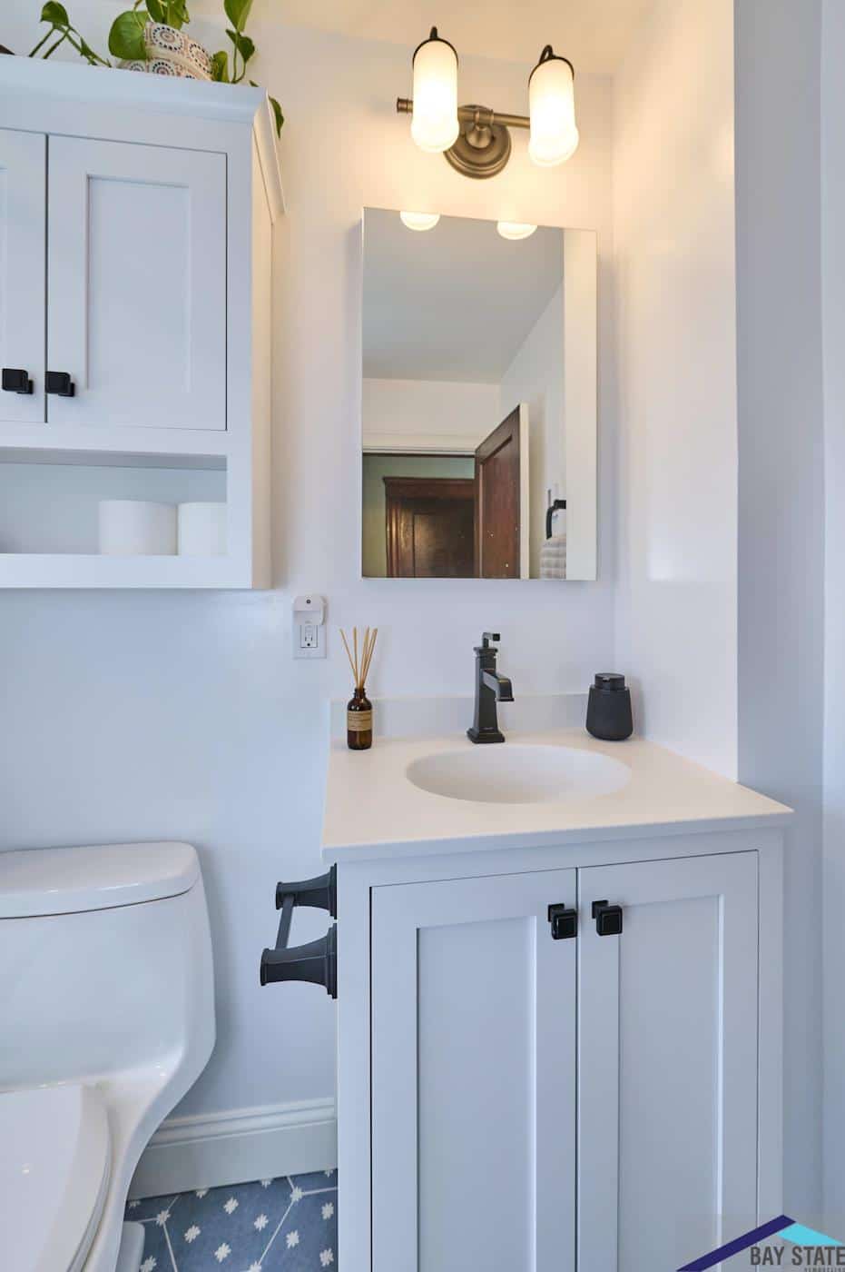 N. Crescent Circuit Boston bathroom remodel shows black hardware, oval sink, and vintage-style vanity sconce