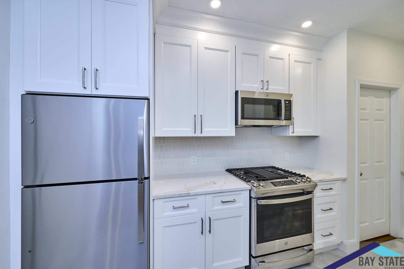 Renovated Norfolk St. Cambridge kitchen with stainless refrigerator, gas range, and white shaker cabinetry