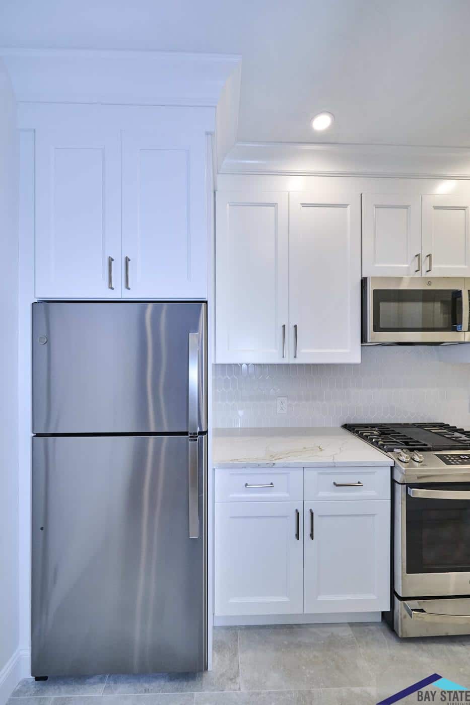 Renovated Norfolk St. Cambridge kitchen with tall cabinetry, crown molding, and stainless refrigerator built in