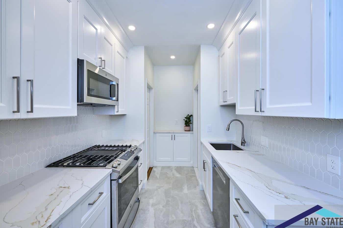 Norfolk St. Cambridge galley kitchen with white cabinets, hexagon tile backsplash, and marbled quartz countertops