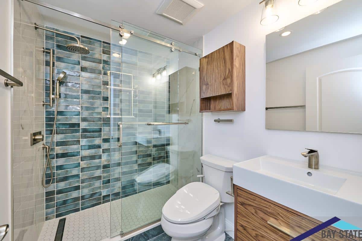 Renovated Kensington Ave. Newton bathroom with teal subway tile shower, glass door, and wood vanity