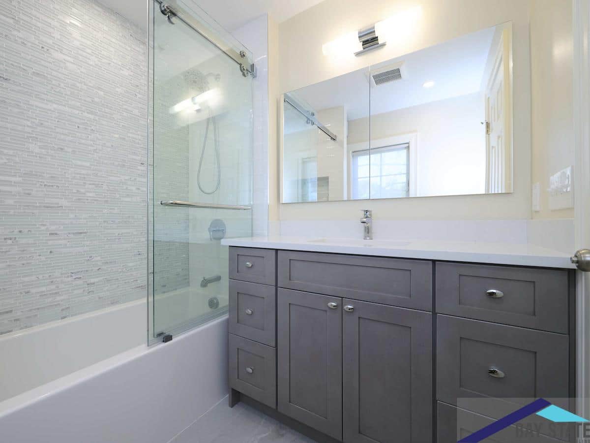 Renovated Chestnut St. Brookline bathroom with gray shaker vanity, white quartz counter, and mosaic tile shower