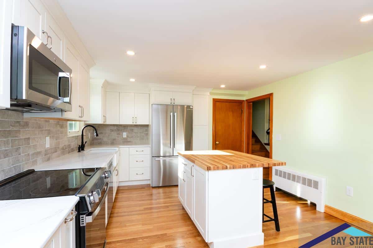 Waltham kitchen on Kingston Rd. with white cabinets, stainless refrigerator, and wood-paneled stairway door