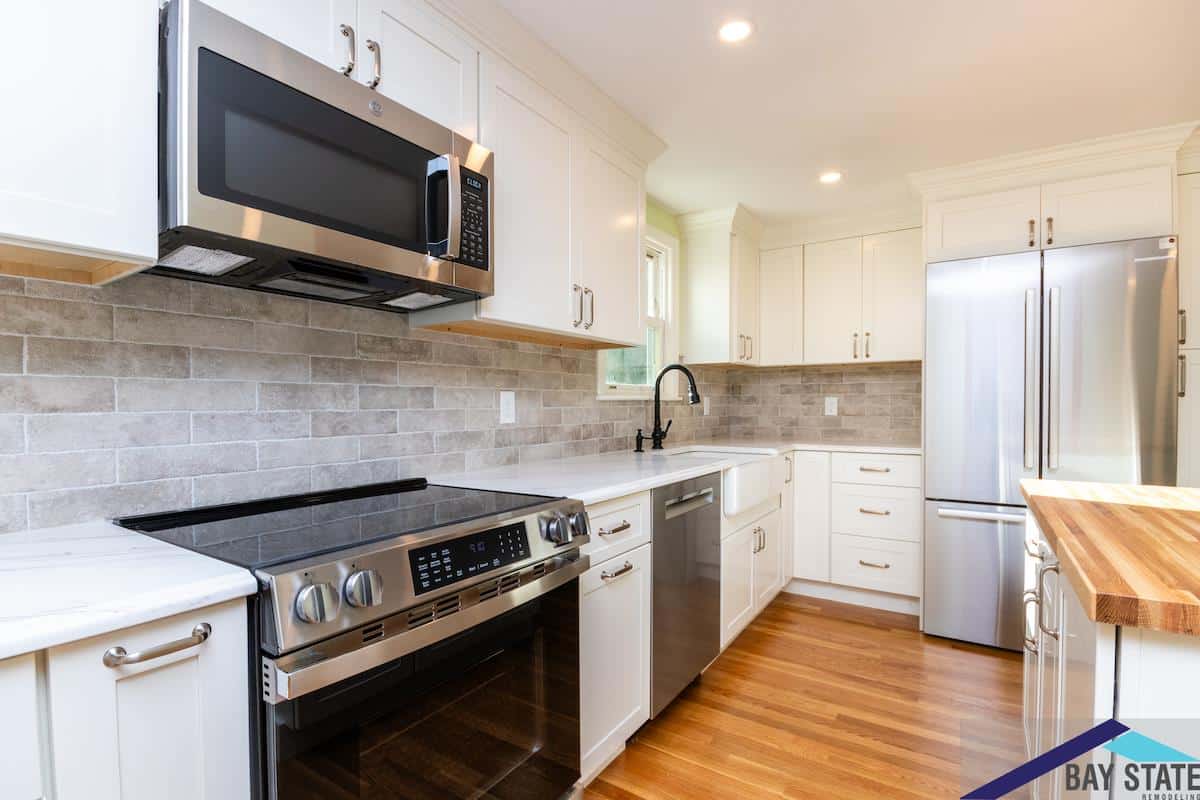 Kingston Rd. Waltham galley kitchen with white shaker cabinets, tile backsplash, and stainless range
