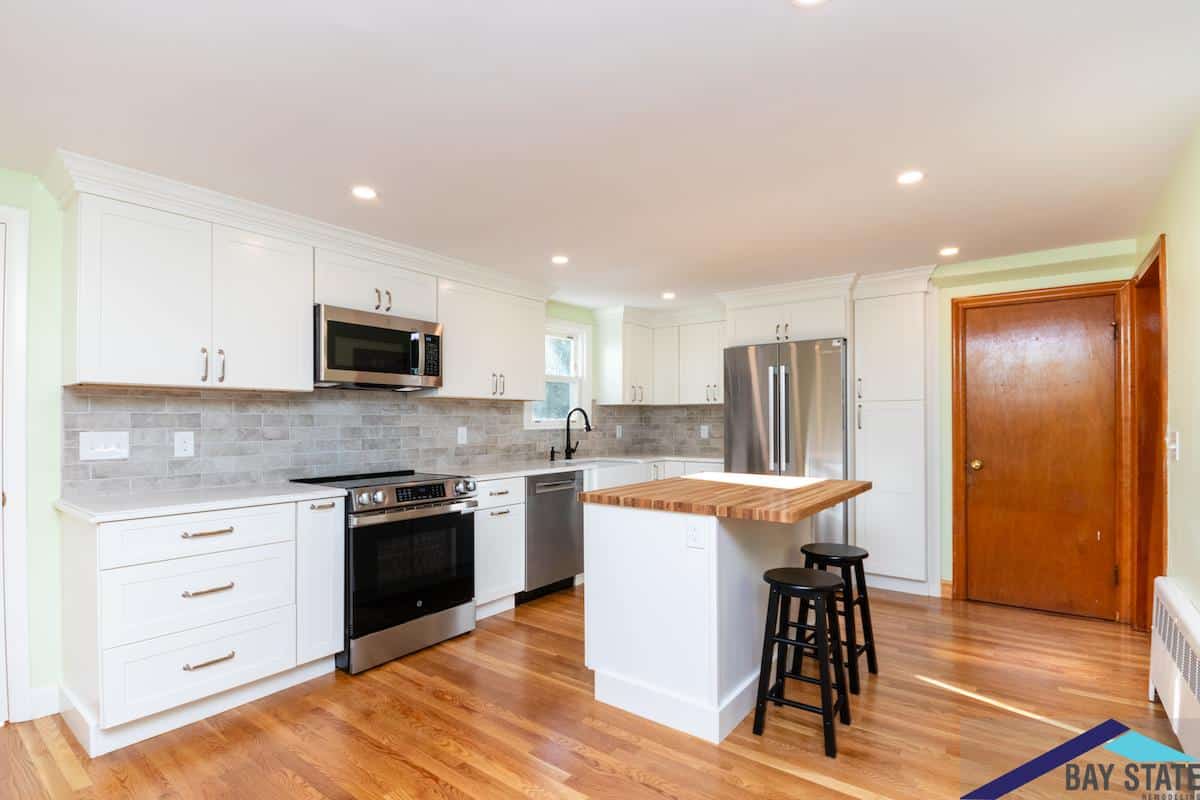 Kingston Rd. Waltham kitchen with white shaker cabinets, gray subway tile backsplash, and butcher block island