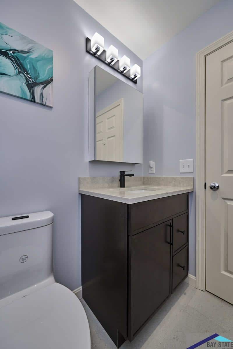 South Commons Lincoln bathroom after renovation with a dark wood vanity, quartz counter, and lavender walls