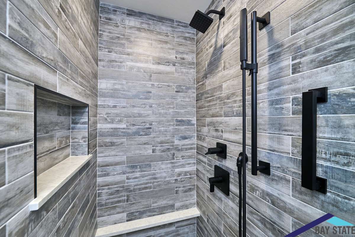 Renovated South Commons Lincoln shower with wood-look gray plank tile, black fixtures, and built-in niche