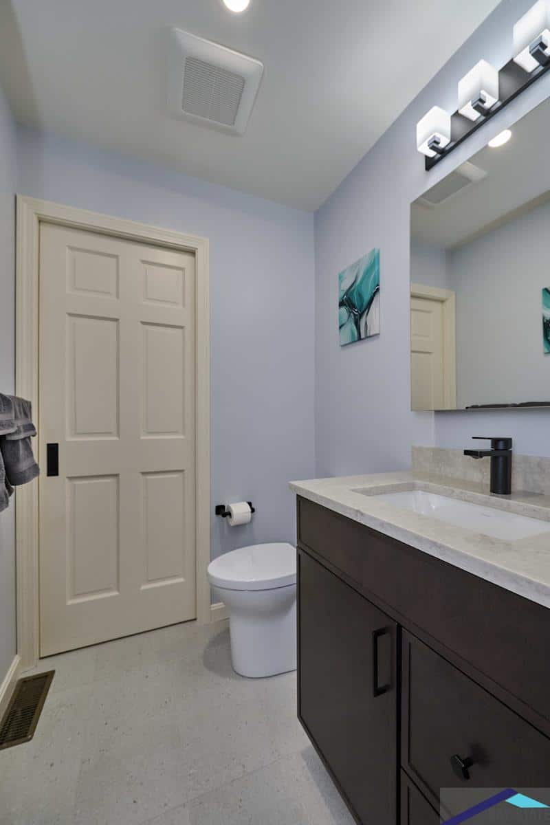 South Commons Lincoln bathroom with dark vanity, marble top, and teal wall art