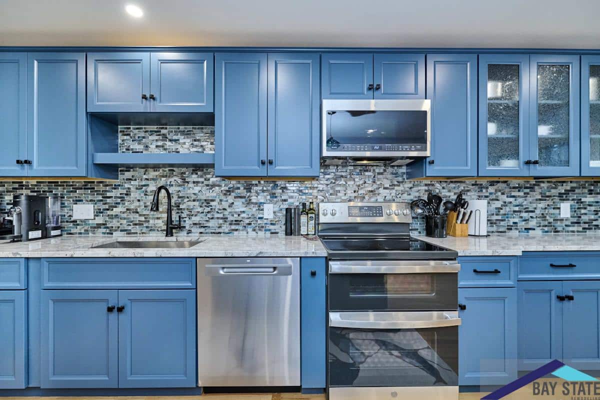 South Commons Lincoln finished kitchen with slate-blue cabinets, mosaic tile backsplash, and stainless appliances