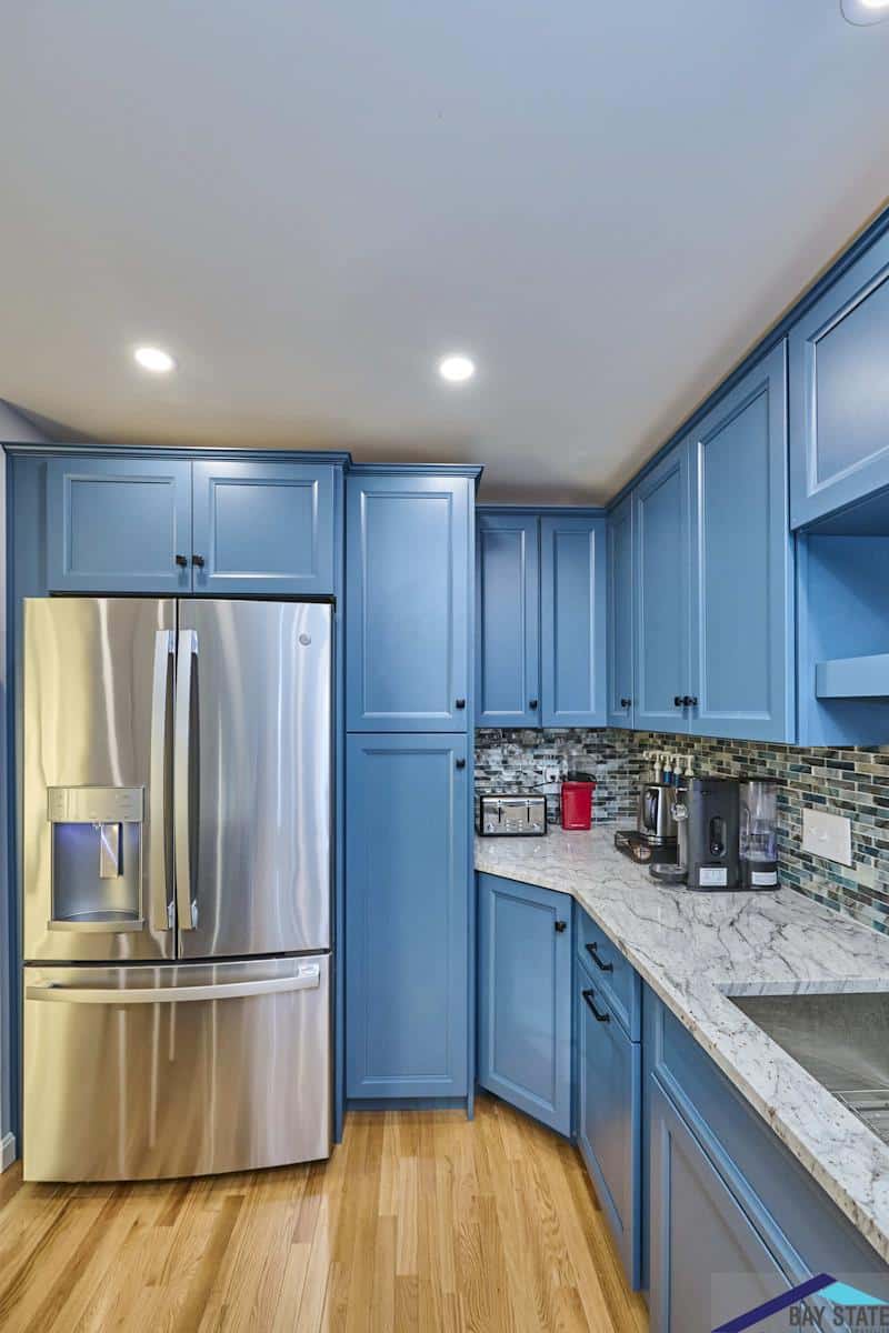 South Commons Lincoln kitchen with blue cabinets, stainless fridge, and tile backsplash