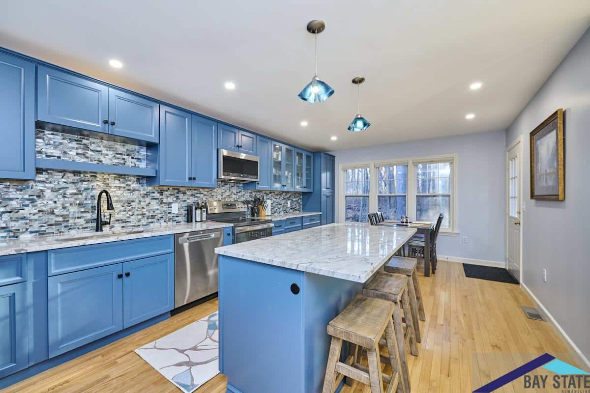 South Commons Lincoln kitchen island with marble counter, pendant lights, and wood stools