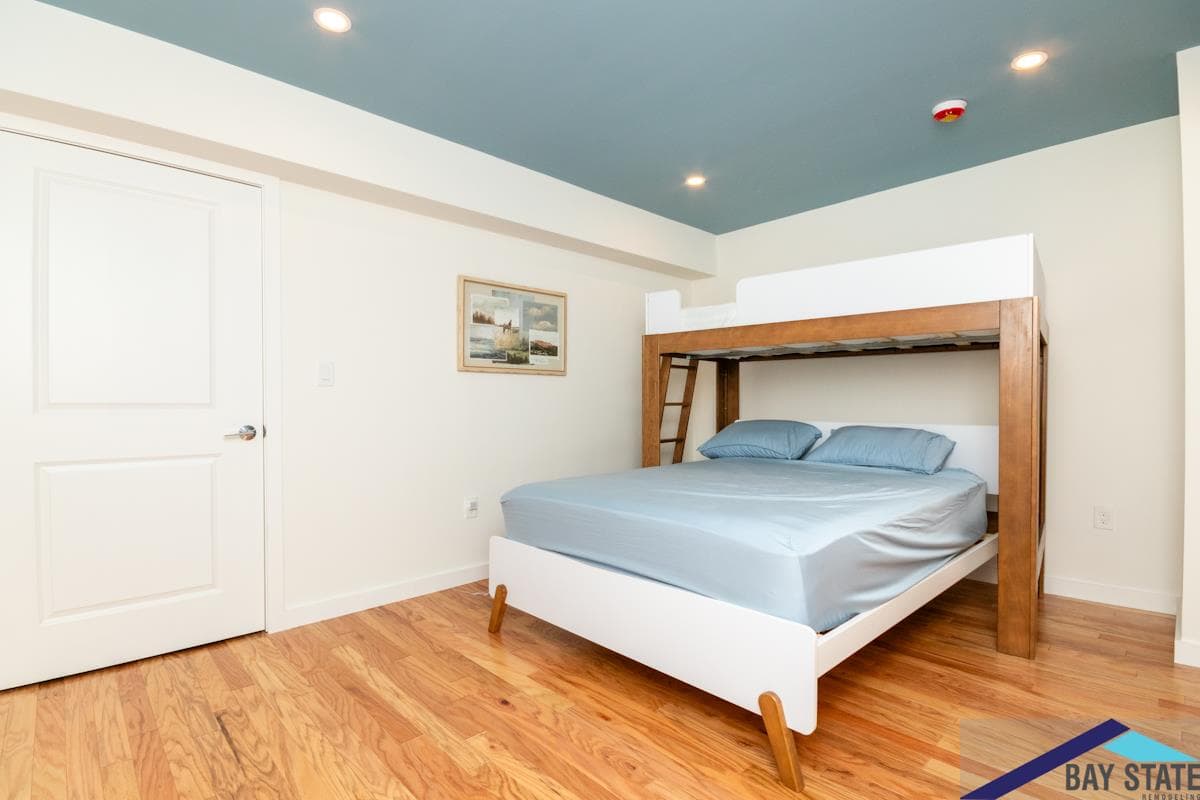 Highland St. Newton bedroom remodel with a built-in bunk bed, blue accent ceiling, and oak floors