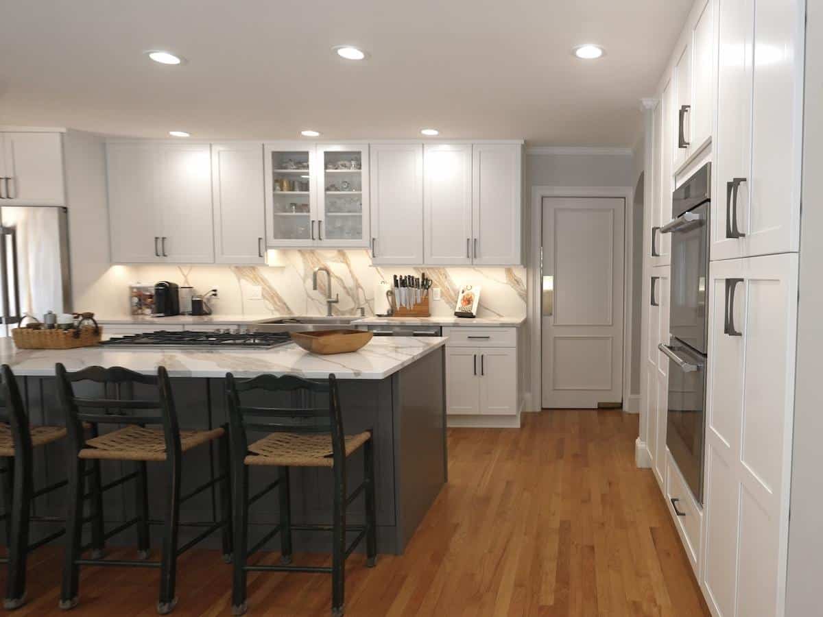 Brook Trail Rd. Wayland kitchen with white shaker cabinets, dark island, and marbled quartz waterfall counters