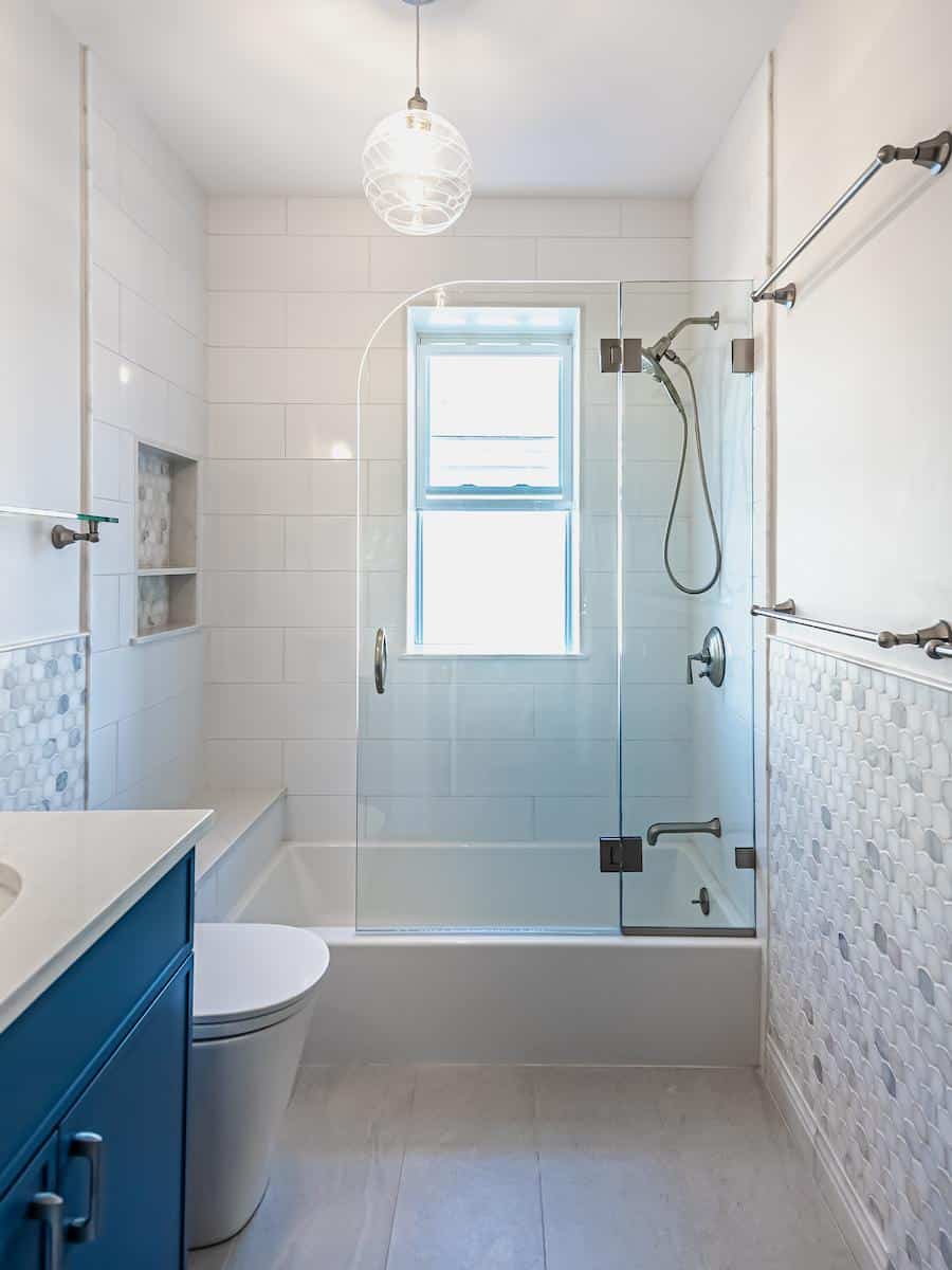 Renovated Tappan St. Brookline bathroom with white subway tile, frameless glass shower, and navy vanity