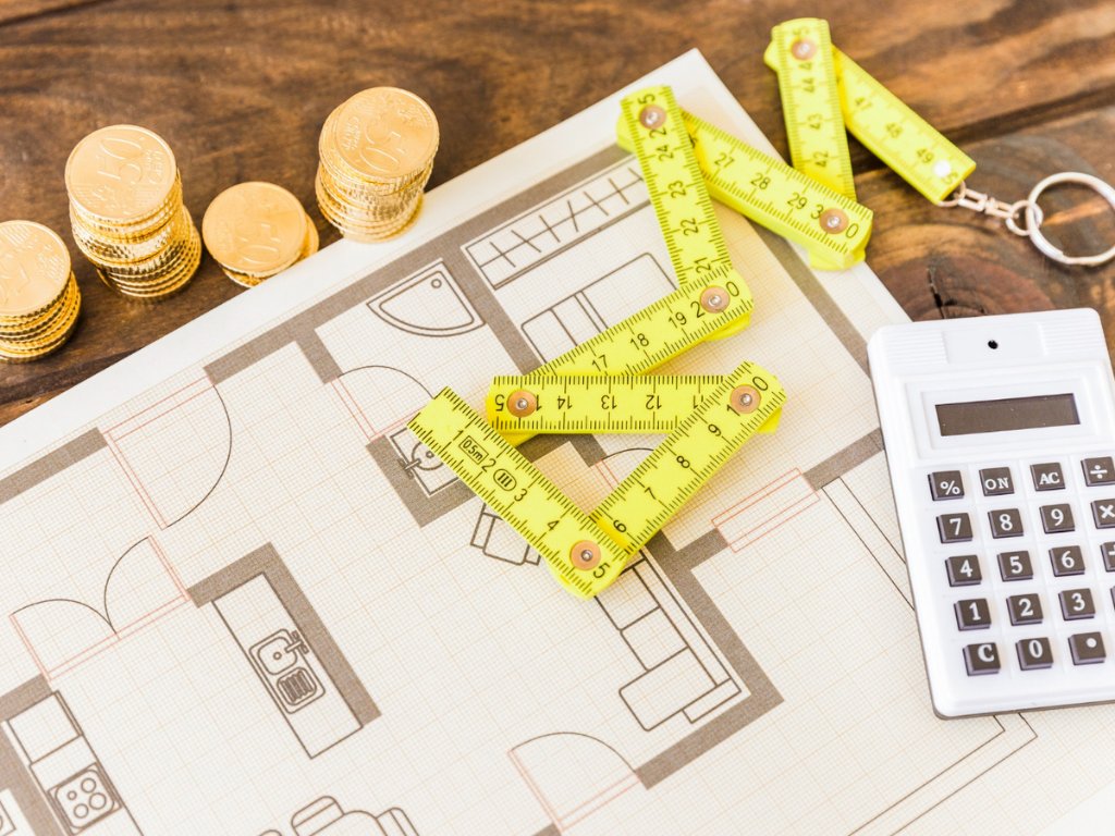 high-angle-view-measure-tape-calculator-stacked-coins-blueprint