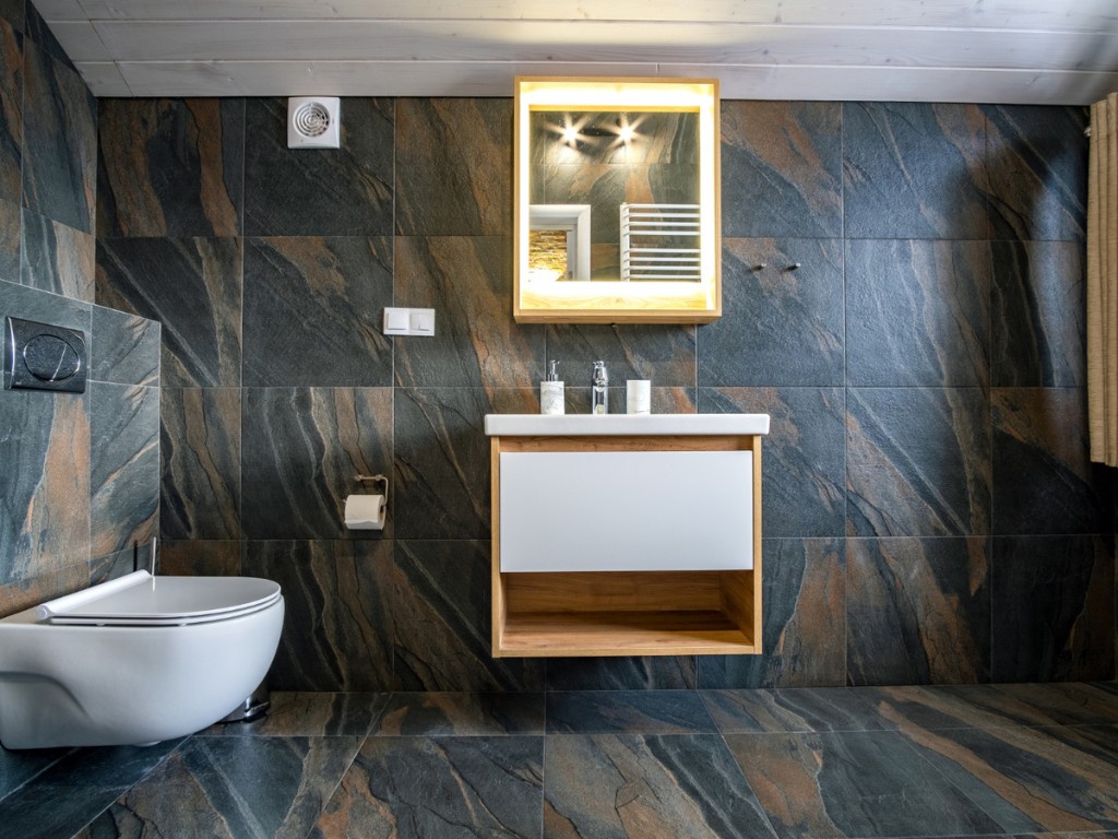 interior modern stylish bathroom with black tiled walls curtain shower place wooden furniture with wash basin big illuminated mirror