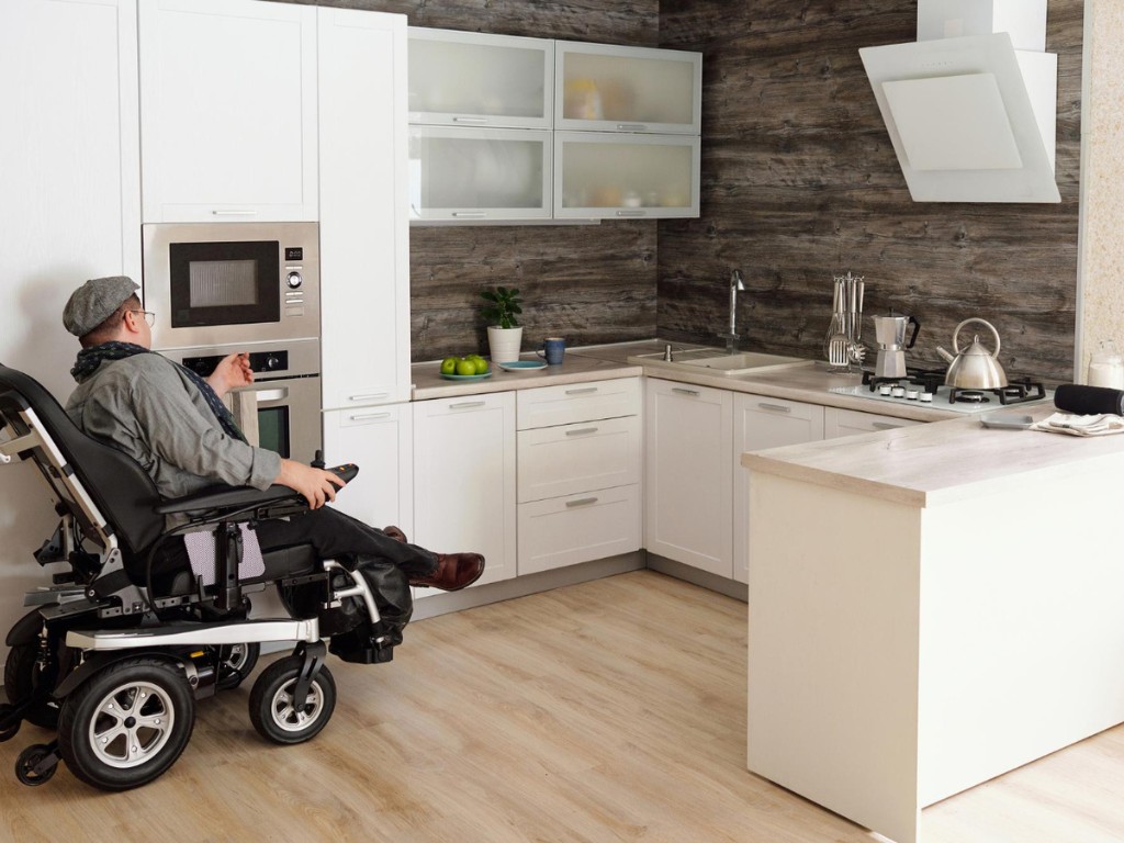 middle-aged-man-with-disability-sitting-by-electric-oven
