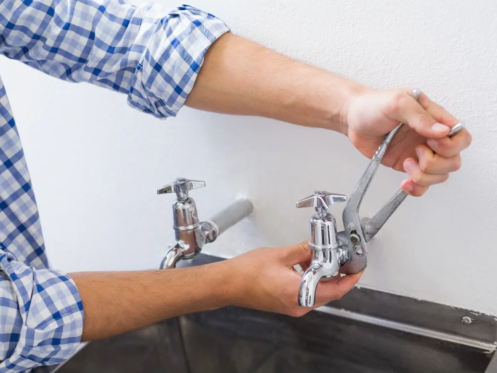 plumber hands fixing water tap with pliers