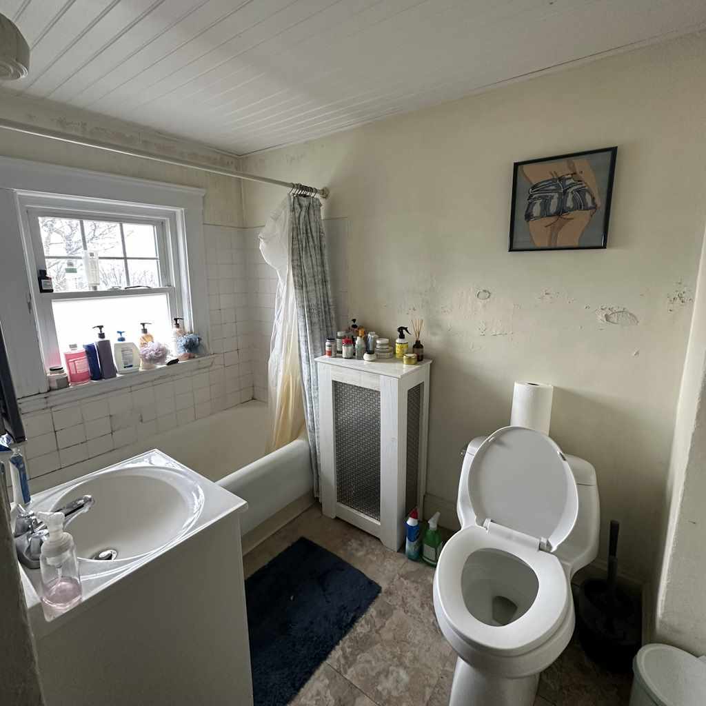 Outdated bathroom with peeling paint, old tiles, and cluttered sink area before renovation at N. Crescent Circuit.