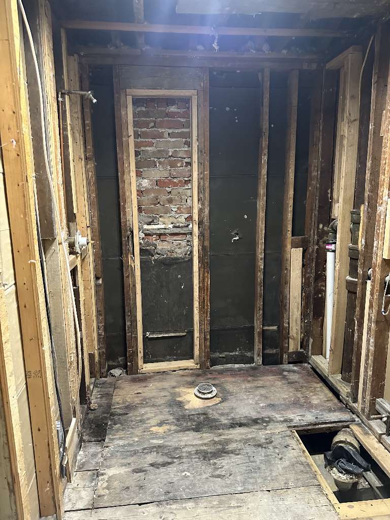 Exposed studs and subfloor during bathroom remodeling process at Kensington Ave, Newton.