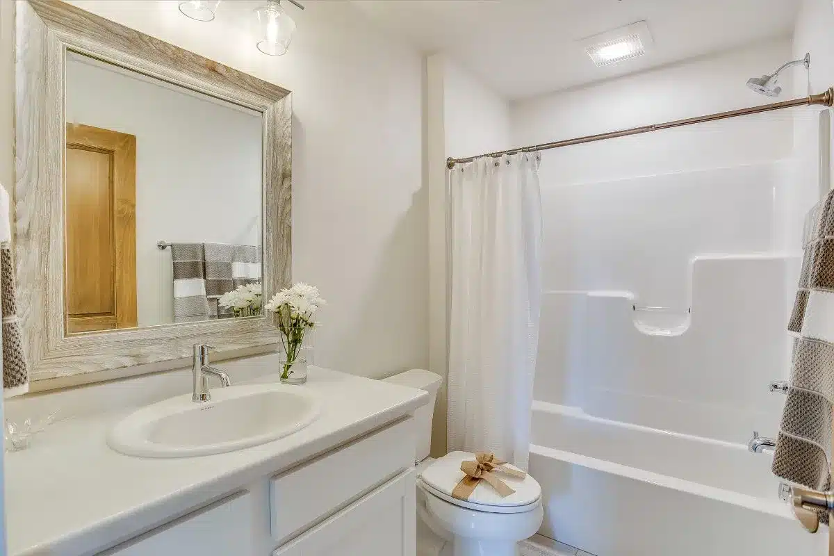 Small bathroom remodel ideas with white vanity, framed mirror, and tub-shower combo in a compact layout