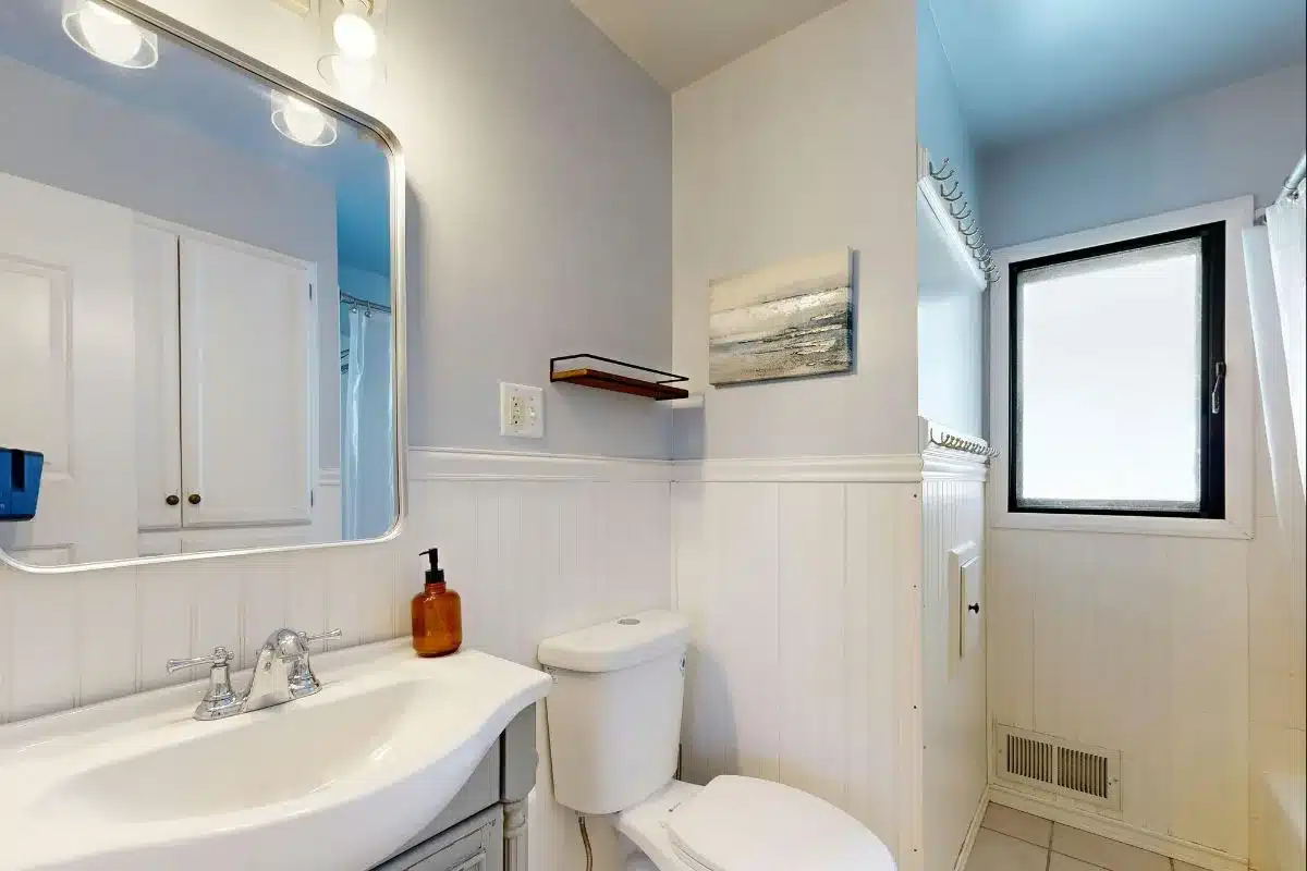 Moody dark-toned bathroom decor ideas with charcoal tile, matte black fixtures, marble pedestal sink, and ambient lighting