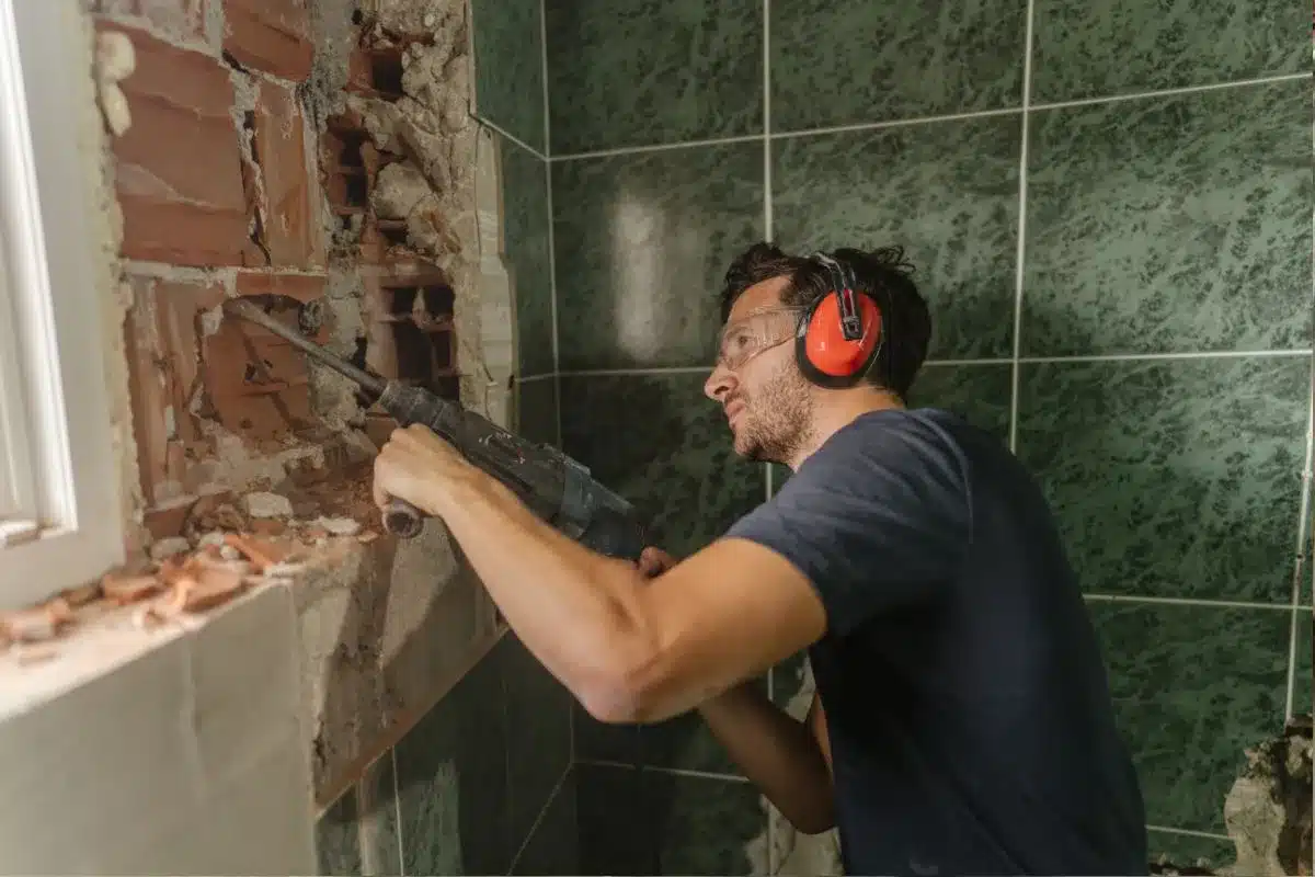 Contractor using a demolition hammer to remove old bathroom tiles during a Boston bathroom renovation