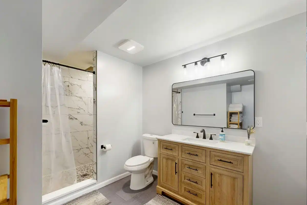 Modern bathroom ideas with a wood vanity, marble-tiled walk-in shower, and black hardware