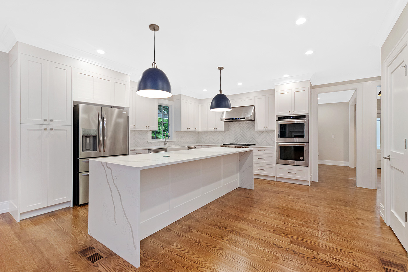 White kitchen cabinets, island counters and dark pendant lights in the Garland Road whole-home expansion, which included a second-story addition. This is a completed project example, not an ADU kitchen.