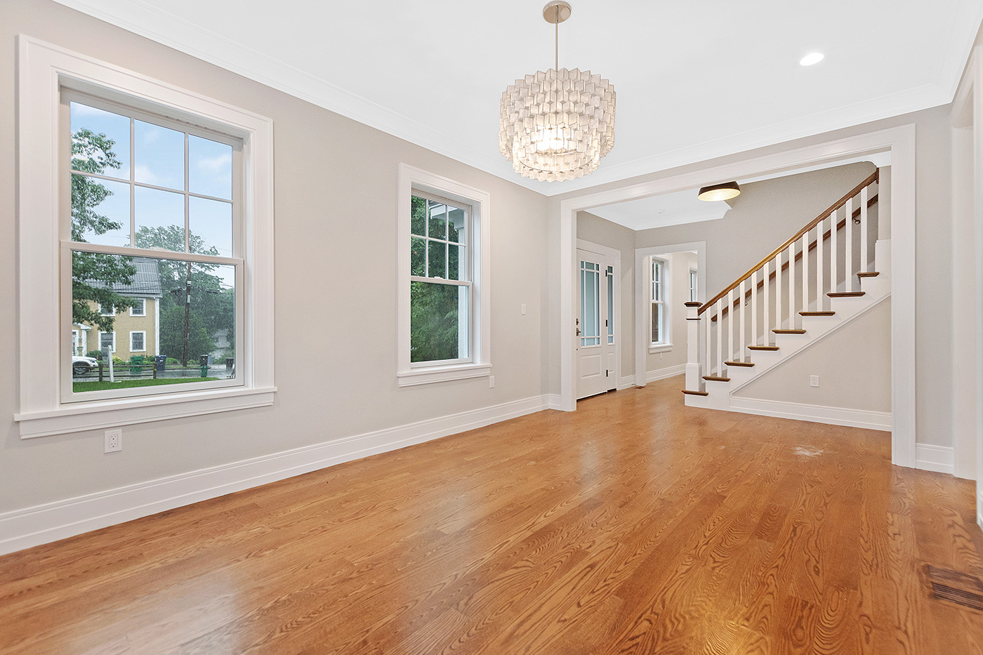 Stair treads, white balusters and a wood-toned handrail beside the finished floor and windows at the Garland Road whole-home expansion.