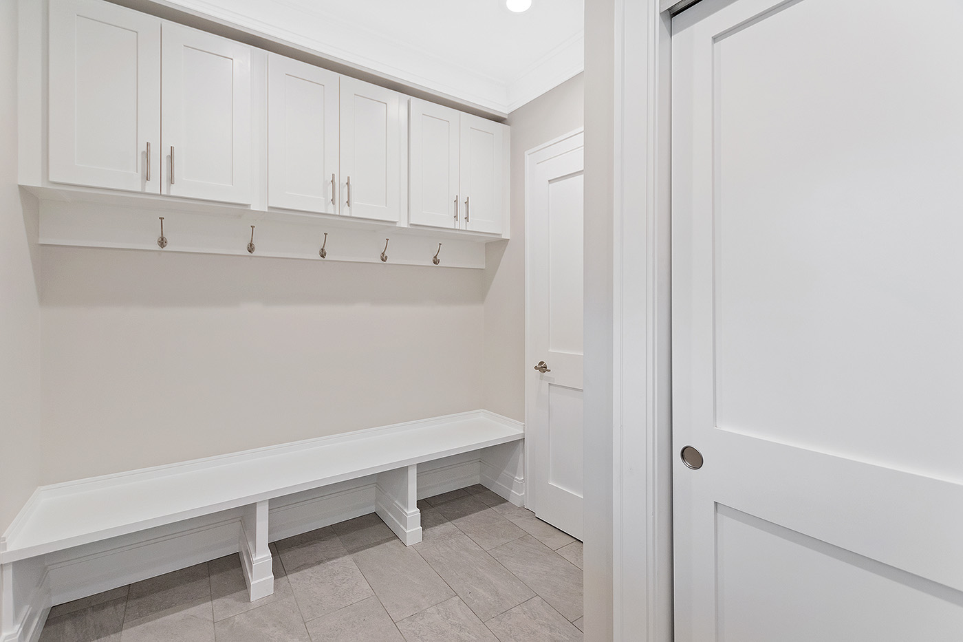 Built-in mudroom cabinets above a bench with coat hooks at Garland Road, Newton.