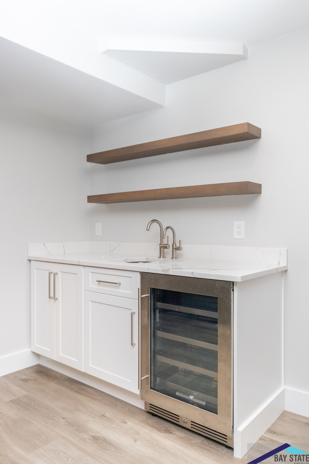 Built-in basement bar cabinets with a sink, faucet, beverage refrigerator and open shelves at East Street, Lexington.